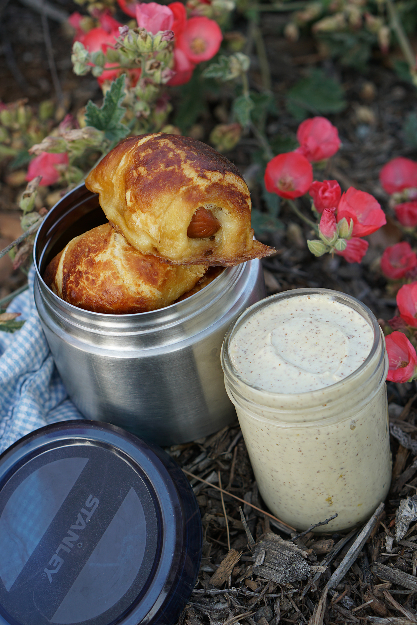 Pretzel Sausage Rolls in a camp thermos with mustard cheese sauce alongside