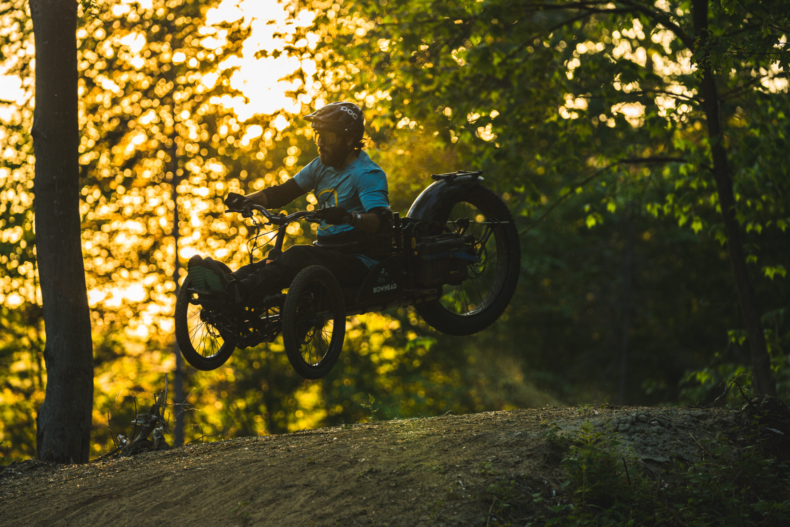 Adaptive mountain biker launching off a jump at golden hour