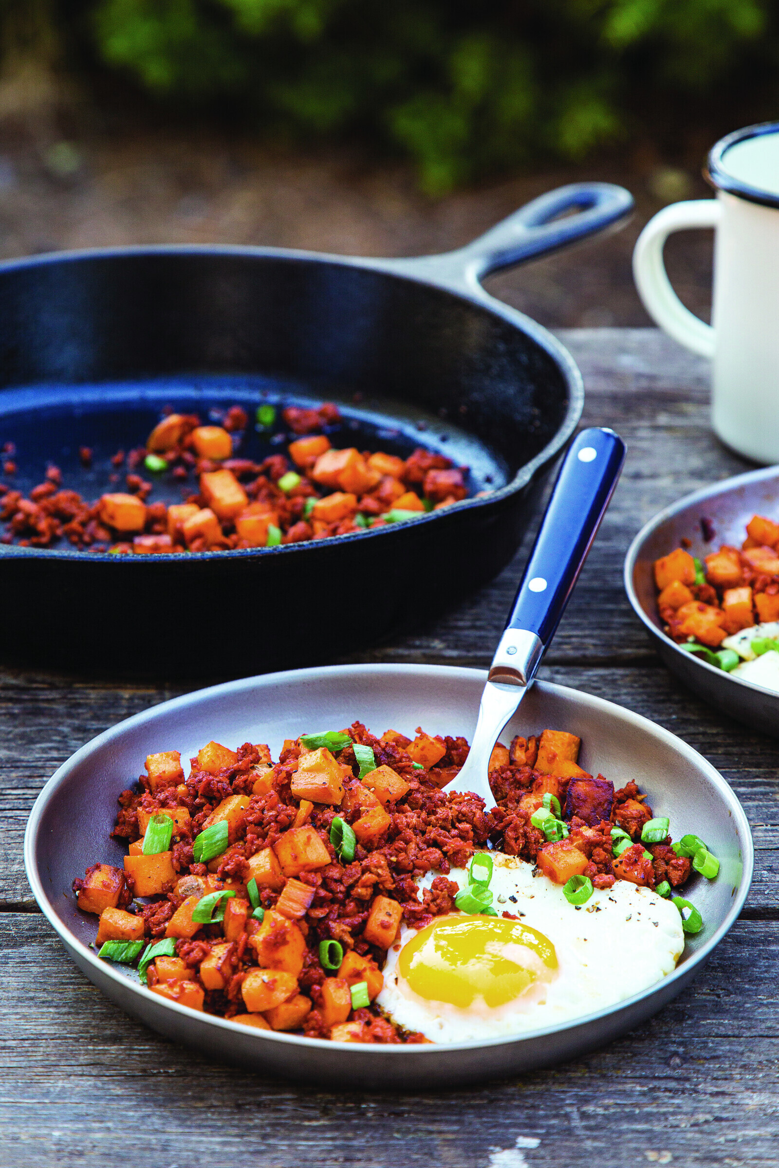 Sweet Potato Breakfast Hash with scallions and eggs in a cast iron skillet
